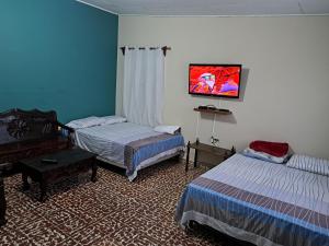 La LimaHostal Lima Verde的一间卧室设有两张床,墙上配有电视。