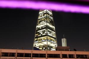 利雅德Business Inn Olaya的一座高大的建筑,晚上有紫色的灯光