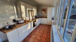 WeltonHolly Cottage, Hidden gem in the Yorkshire wolds的厨房配有白色橱柜和瓷砖地板。