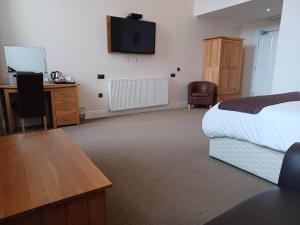 坎贝尔城Grammar Lodge Guest House的酒店客房配有一张床、一张书桌和一台电视。