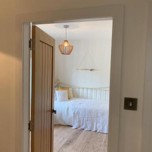 GlamisWoodview Cottage的卧室配有白色的床和吊灯