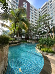 Klandasan KecilOne bedroom apartment at Borneo Bay City的棕榈树和建筑度假村内的游泳池