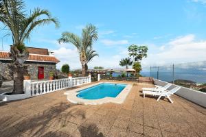 洛斯雷亚莱霍斯Finca Viña Maria的一座带游泳池和白色椅子的房子