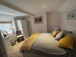 布里德波特Cottage en-suite room with private lounge的一间卧室配有一张带黄色枕头的大床