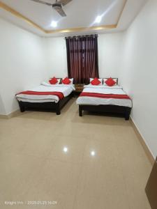 古瓦哈提Hotel Knight Inn Airport的一间卧室配有两张带红色枕头的床