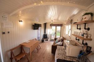 兰迪德诺Luxury Twin Shepherds Hut - Cosy & Romantic的一间客厅,客厅配有沙发和桌子,位于一个小房子里