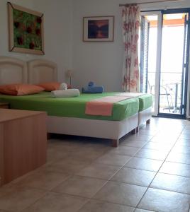 Agios Ioannis KaspakaStudios Edem的一间卧室配有一张带绿色和粉色床单的床