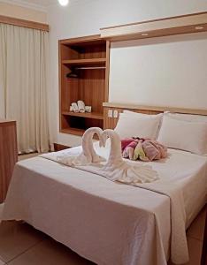 波苏斯-迪卡尔达斯Hotel Lux的卧室里床边有两只天鹅