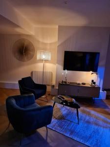 马孔Escapade Mâconnaise Spa-Sauna-Ciel de pluie tropicale-Champagne Nuit Romantique的客厅配有2把椅子和平面电视