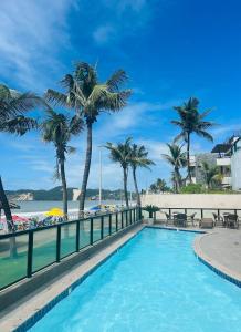 纳塔尔KING's FLAT HOTEL NATAL的棕榈树海滩旁的游泳池