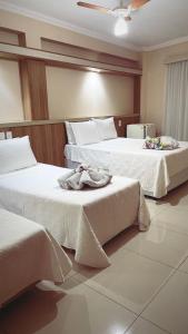 波苏斯-迪卡尔达斯Hotel Lux的两张位于酒店客房的床,配有毛巾