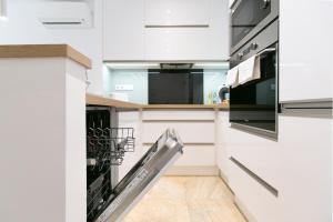 塞格德Mentha Apartman Szeged的厨房配有洗碗机,厨房配有白色橱柜