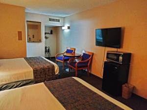 盐湖城大都会盐湖城酒店的酒店客房设有两张床、一张桌子和电视。
