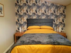 奥赫特拉德Sycamore Lodge Auchterarder的一间卧室配有一张带黄色床单和壁纸的床