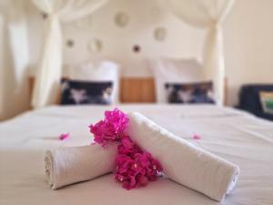 Quartier Morne PavillonHotel Le Manguier的铺在床上的带粉红色鲜花的滚动毛巾