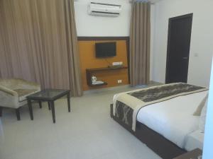 诺伊达Tavisha Villa Flim City Road Dadri Road的一间卧室配有一张床、一把椅子和电视