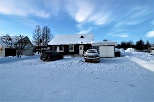 基律纳RIBO Apartment Arctic的两辆汽车停在房子前面的雪地里