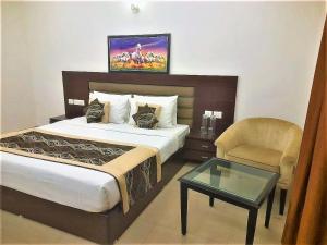 诺伊达Tavisha Villa Flim City Road Dadri Road的一间卧室配有一张床、一把椅子和一张桌子