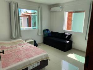 圣若泽-达科罗阿格兰迪Vila Bangalô的一间卧室配有一张床、一张沙发和两个窗户。