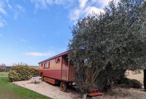 拉聂Roulotte chez Manon en Luberon的停在树旁边的红色拖车