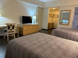 蒙特雷中央公园酒店 的酒店客房设有两张床、一张桌子和一台电视。