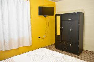 莫科阿Hotel Tari的一间卧室配有黑色橱柜和黄色墙壁上的电视
