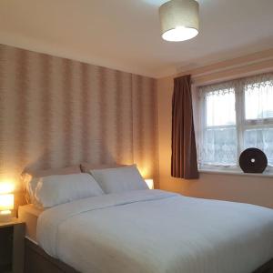 WainscotIdeally located contemporary 3 bed spacious house的卧室设有一张白色大床和一扇窗户。
