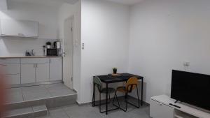 海法Studio Apartment 12 Minutes from Bahai's garden的厨房配有桌子和两把椅子以及电视