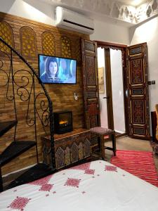 非斯Dar Dahab的一间卧室配有一张床,墙上配有电视