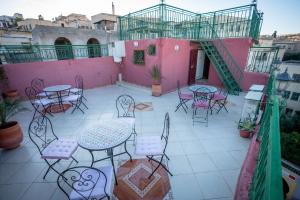 非斯Dar El Karam Fez的粉红色建筑前方带桌椅的庭院