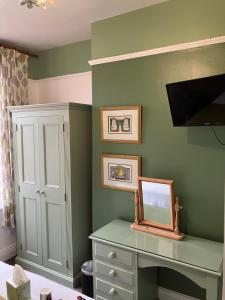 埃文河畔斯特拉特福Broadlands Guest House的一间卧室设有绿色的墙壁和一张带镜子的书桌