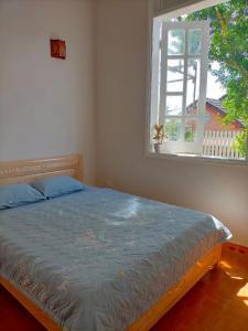 Gia NghĩaLy's homestay的一间卧室配有一张带蓝色床罩的床和窗户。
