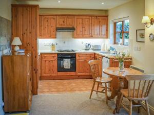 North MundhamHoneysuckle Cottage的厨房配有木制橱柜和桌椅