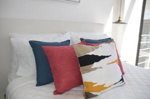 危地马拉Cozy Stays Cayala Apartments 602的一张白色的床,上面有色彩缤纷的枕头