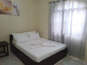 长滩岛Tresha Lance Apartelle的一间卧室配有一张带白色床单的床和一扇窗户。