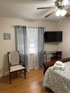 桑福德Sanford Lake Mary Quiet Rooms的一间卧室配有一张床、一把椅子和电视