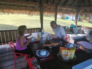 AfaahitiVai Iti Lodge的坐在餐桌旁吃饭的男人和女人