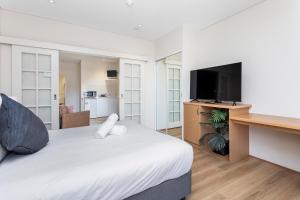 珀斯Perth Cbd Retreat Victoria Ave 1br Apt的一间卧室配有一张床和一张书桌及电视