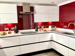 彭赞斯Stylish Sea View Apartment with Parking的厨房配有白色橱柜和红色墙壁