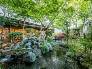 笛吹市Japanese Onsen Ryokan Kohakuen的花园内种有岩石和树木的瀑布