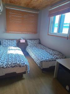 木浦市Leehakjang guesthouse的一间卧室配有两张床和电视。
