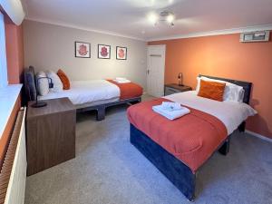 史云顿BLUNSDON LODGE - Spacious Bungalow, High Speed Wi-Fi, Free Private Parking, Garden的配有两张带橙色墙壁的床的房间