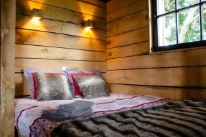 AttreLa cabane du cerf et son sauna的木墙和窗户的客房内的一张床位