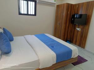 艾哈迈达巴德HOTEL ROYAL GRAND的一间卧室配有一张带蓝色枕头的床和电视。