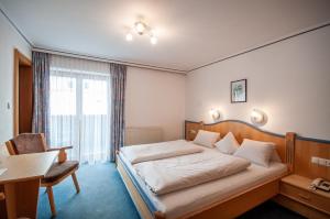 蒂罗尔-基希贝格福鲁克斯图克塔嫩霍夫酒店的酒店客房配有一张床、一张桌子和一把椅子。