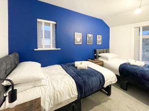 史云顿SHRIVENHAM - Spacious Home, High Speed Wi-Fi, Free Parking, Garden的一间卧室设有两张床和蓝色的墙壁