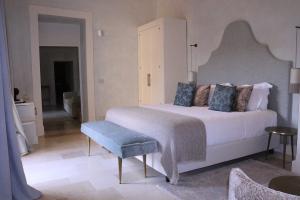 莱切Palazzo Maresgallo Suites & SPA的一间卧室配有一张白色大床和蓝色长凳
