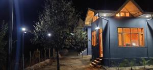 ShogiLacasa Luxury Stays的夜晚在前面有一棵树的蓝色房子