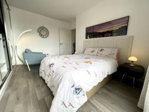 巴纽Superbe Appartement en Résidence T3,Options Clim et parking, lave-linge的卧室配有一张床,墙上挂着一个钟