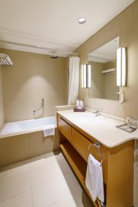 马斯喀特Levatio Suites Muscat, a member of Radisson Individuals的一间带水槽、浴缸和镜子的浴室